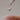 Dropper with a drop of liquid held by a hand with pink nail polish against a neutral background