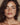 Close-up of a woman with wavy brown hair and a neutral background that had full face Botox in Midtown NYC at Dr Cris Studio