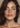 Close-up of a woman with wavy brown hair and a neutral background that had full face Botox in Midtown NYC at Dr Cris Studio